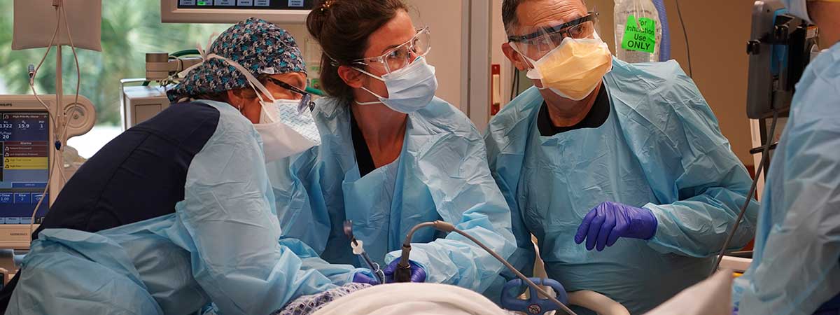 tampa bay times photo of covid ward clinicians helping a patient