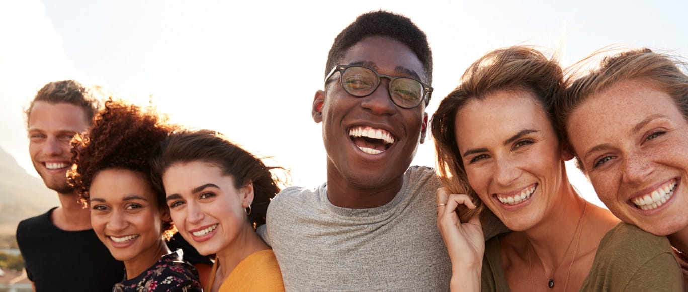 A diverse group of friends smiles for a photo.