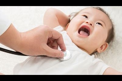 A doctor listens to the heartbeat of a happy baby.