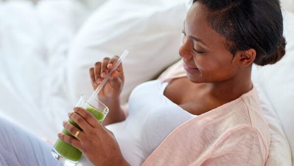 pregnant woman sitting on couch with green container