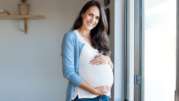 pregnant woman by screen door smiling