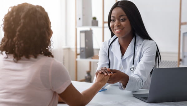 smiling doctor sitting across from woman holding hands