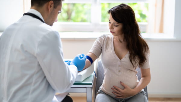 a doctor holding the arm of a pregnant woman holding her stomach