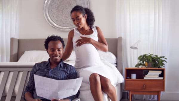 a man and woman sitting down and reading from off a pamphlet