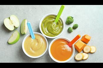 Bowls with baby food on grey background