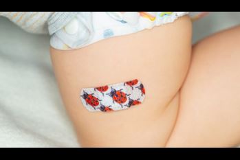Colorful patch on the thigh of a young child after vaccine injection