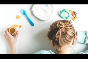 tired mother with her head down surrounded by baby items