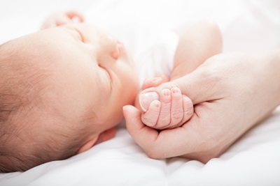 Newborn baby holding mother's thumb