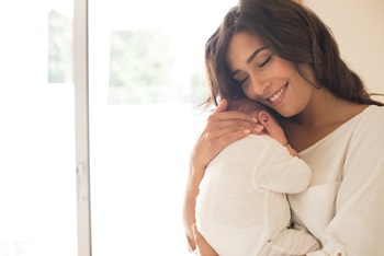 A young woman holding her newborn baby in her arms