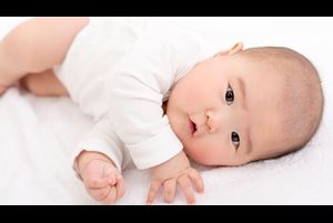 Baby in white onesie rolling over