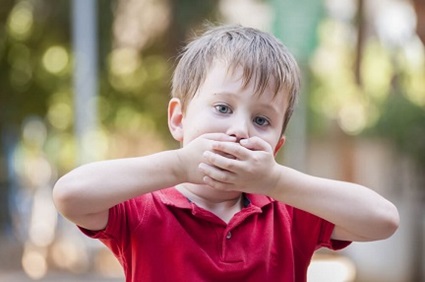 A child holding his mouth while he has the hiccups