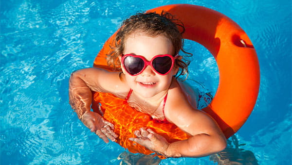 little girl floating in a pool with sunglasses and floatie