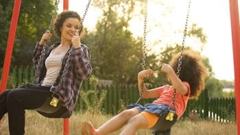 babysitter and child swinging outside