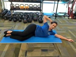 A woman demonstrates the oblique crunch exercise.