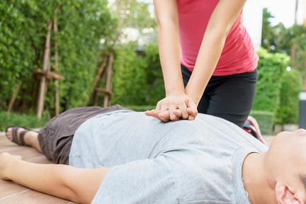 woman in a pink shirt giving a male cpr