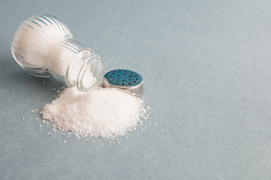 salt spilled out of a salt shaker on grey surface