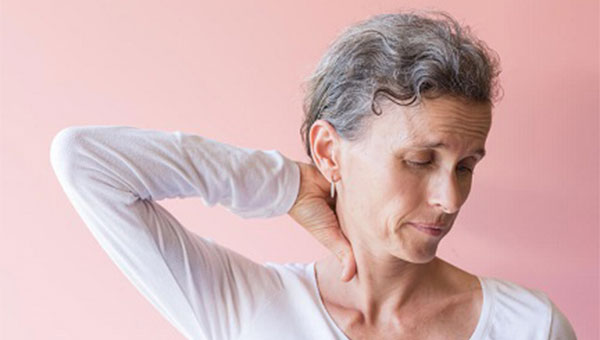 older lady standing with her head turned and massaging her neck