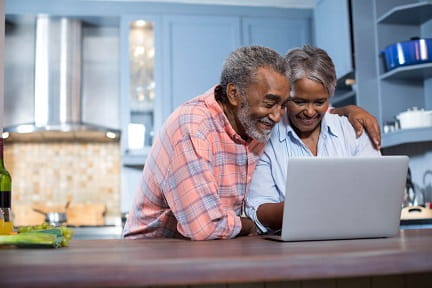mature couple in a kitchen, looking at a laptop