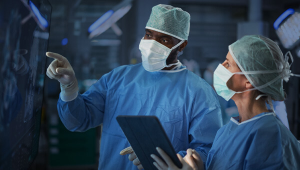 Two surgeons looking at patient information in an operating room.