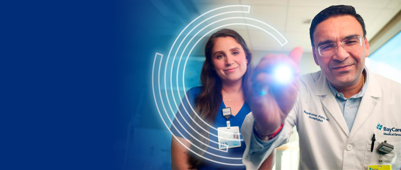 Doctor shining a penlight and a nurse behind him simulating an examination