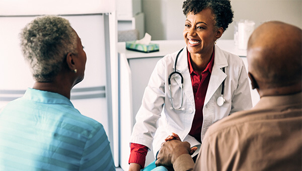 An elderly couple faces a smile female doctor.