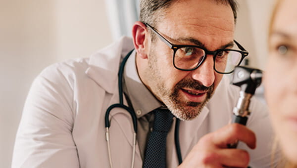 A doctor looking inside a patient's ear.