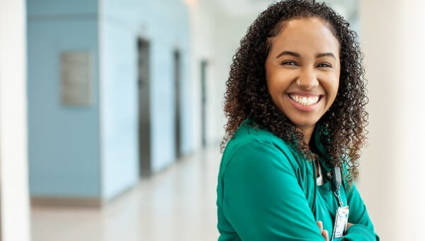 ally nolasco smiling in hallway wearing green scrubs