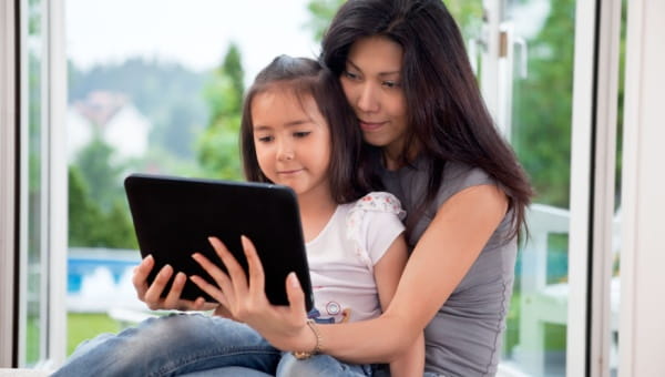 Pediatric Virtual Visits with BayCareAnywhere® A child sitting on her mothers lap in front of a tablet device.