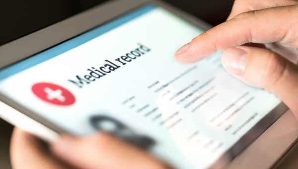 Tablet being held with medical record title on its screen. 