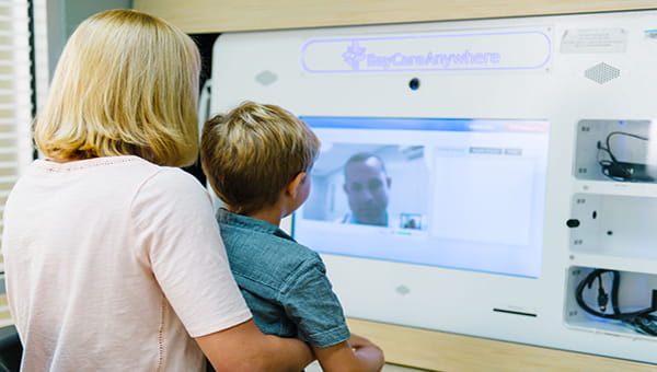 Mother and son have a walkin care visit at publix kiosk