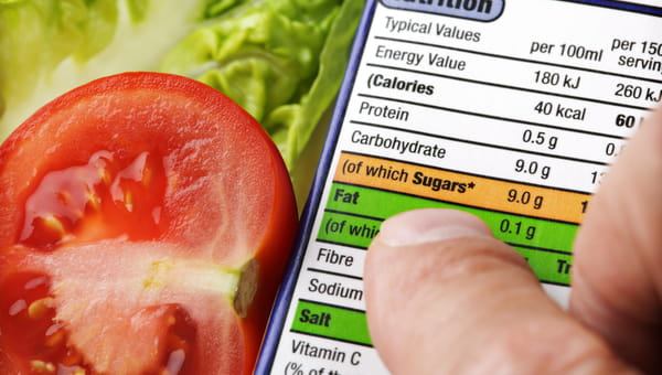 Reading a nutrition label on food packaging with fresh salad background
