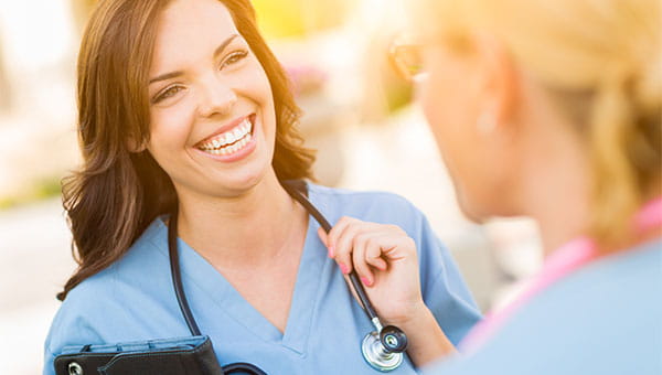 A smiling resident talks with another resident with her back to the camera.
