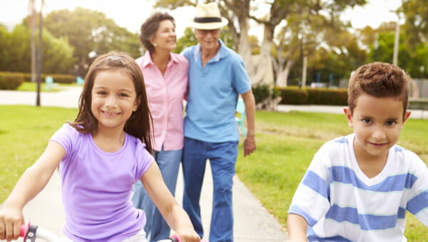 Niños montando en bicicleta con adultos caminando detrás de ellos