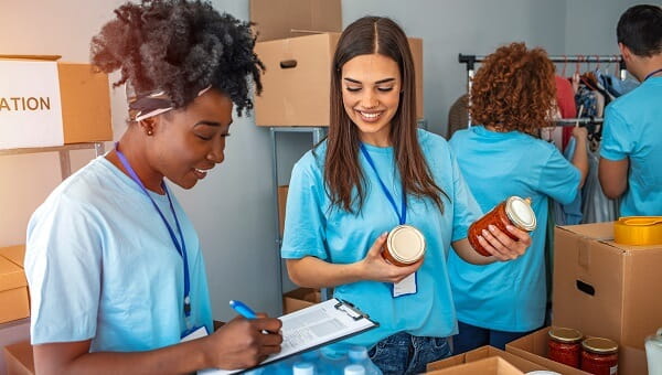 happy volunteers separating donation boxes and clothes