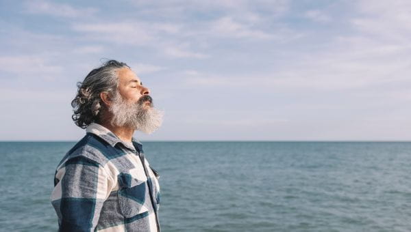 Man taking a deep breath by the ocean
