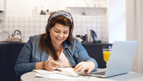 a woman smiling sitting at her desk with her laptop