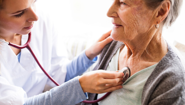a female doctor holding a stethoscope to a patient's chest
