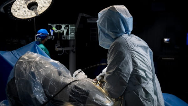 A physician performs surgery with robotic surgical technology.