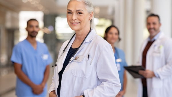 A female doctor smiles for a photo with three other providers in the background.