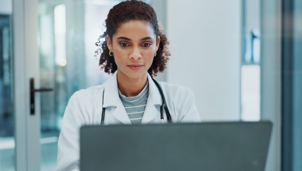 A female doctor looks at a computer screen.