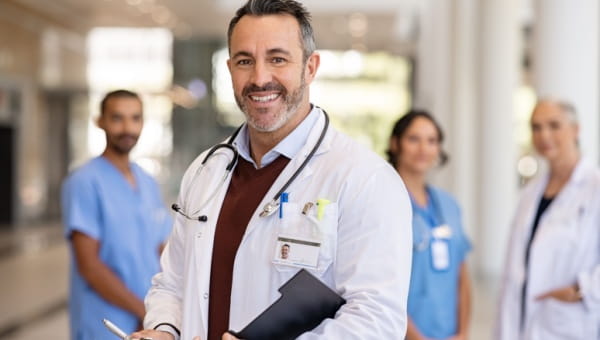 A group of physicians and nurses pose for a photo in a hospital.