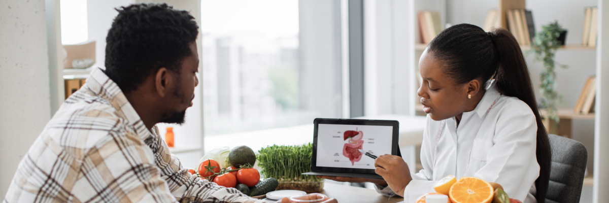 St. Anthony's Heartburn and Swallowing Center A female nutritionist sharing information about digestion on a tablet to a male patient in a well lit room.