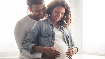 A husband is embracing his pregnant wife.