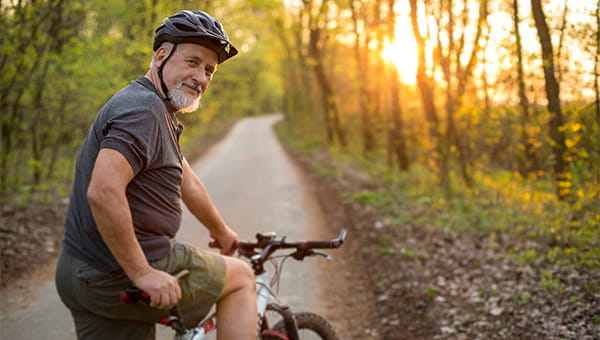 Man with gray beard riding a bike in the woods