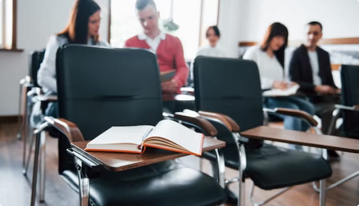 group of people in a classroom with empty seats in the front row.