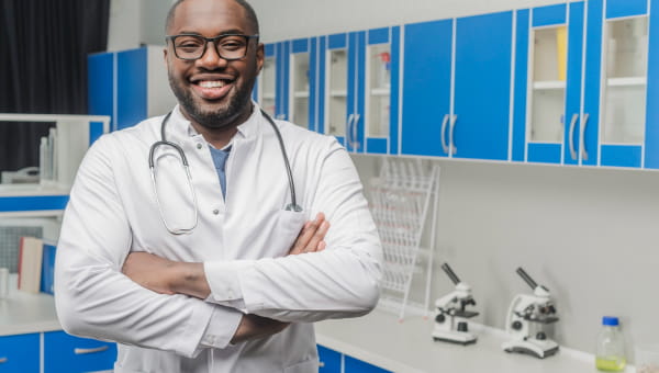 Doctor standing in a lab smiling with crossed arms