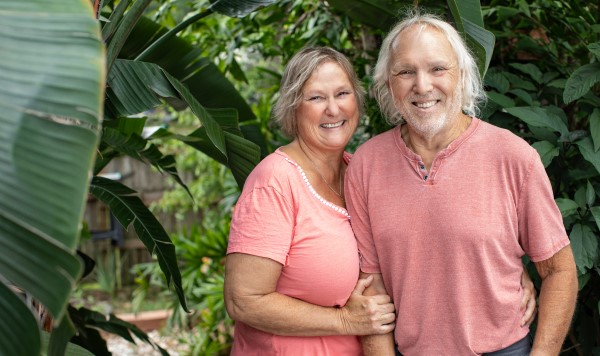 BayCarePlus Member, Steven and Lisa, smile in front of some tropical foliage. 