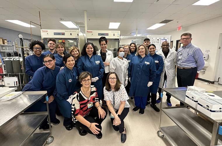 A large group of health care professionals posing in the laboratory they work in.