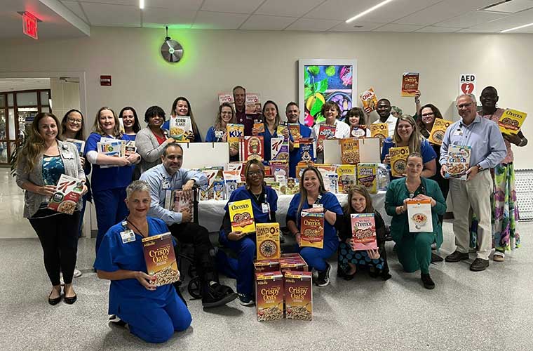 A group of people holding cereal boxes and breakfast food to show support for donation.