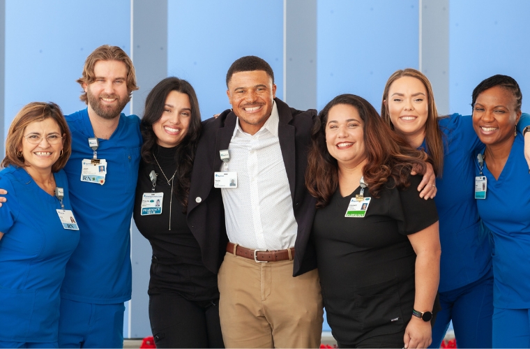 A diverse group of health care professionals in business attire and blue and black scrubs.